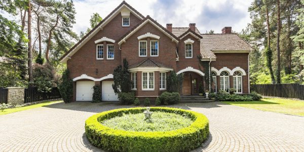 Front view of a driveway with a round garden and big, english st